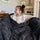 Young girl sitting comfortably in a charcoal ripple plush blanket