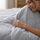 Woman touching a gray cooling comforter with a soft smooth surface
