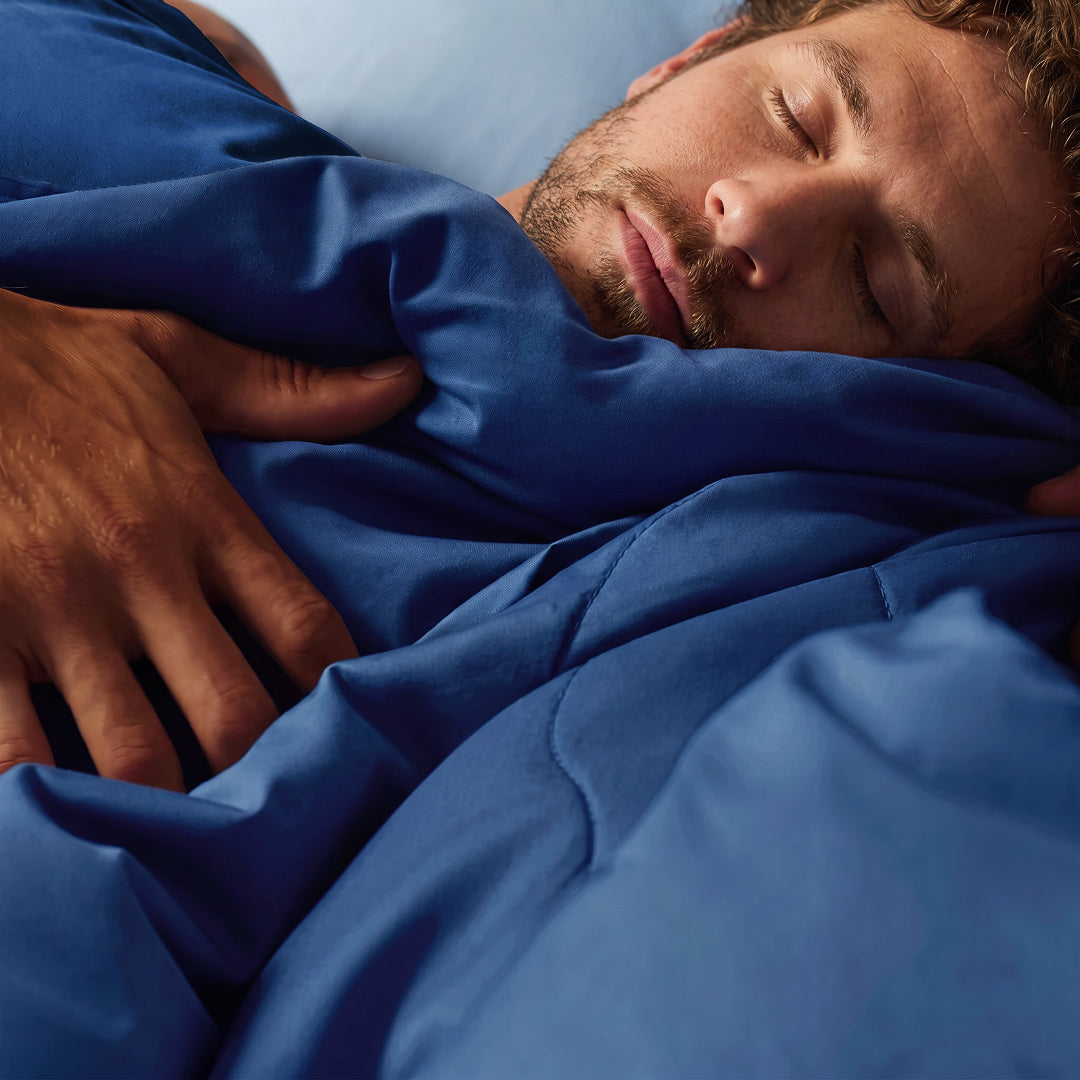 Man sleeping under a navy cooling comforter with smooth cool-touch fabric